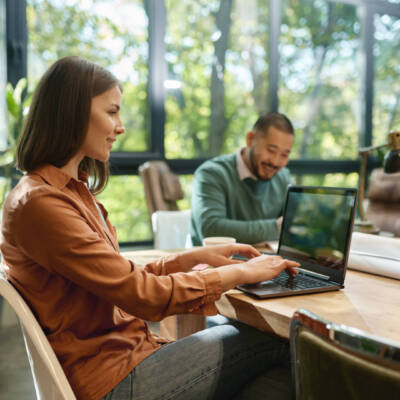 Smiling professional young businesswoman using laptop in coworking space